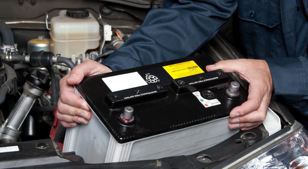 A car mechanic replaces a battery.