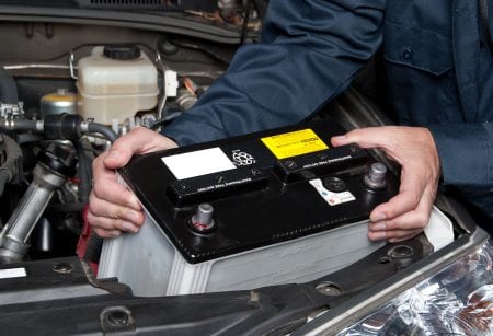 A car mechanic replaces a battery.