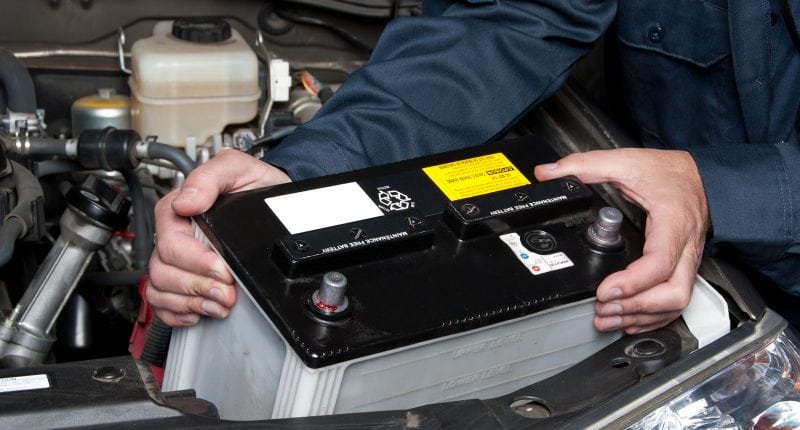 A car mechanic replaces a battery.