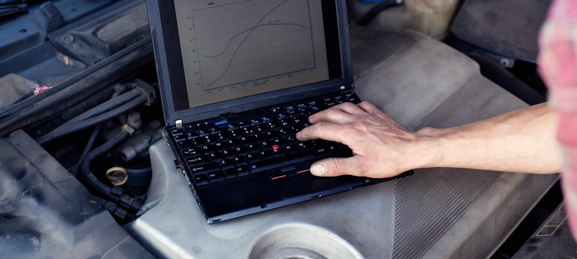 Car mechanic with laptop checking enine